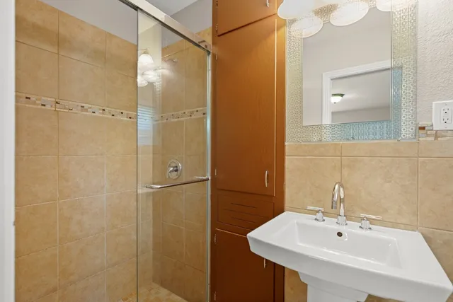 a bathroom with a sink shower and mirror