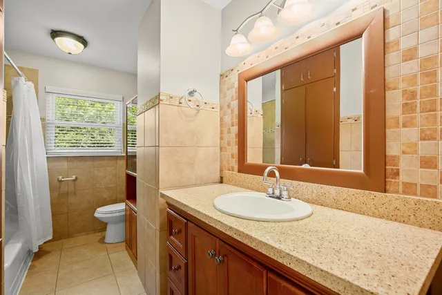 a bathroom with a granite countertop sink a toilet a mirror and shower