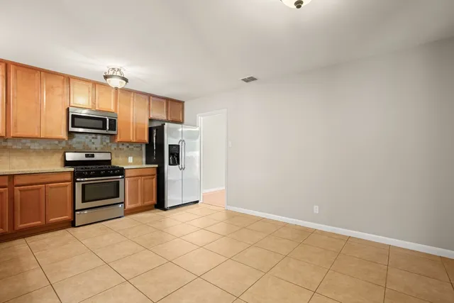 a kitchen with granite countertop a refrigerator and a stove top oven