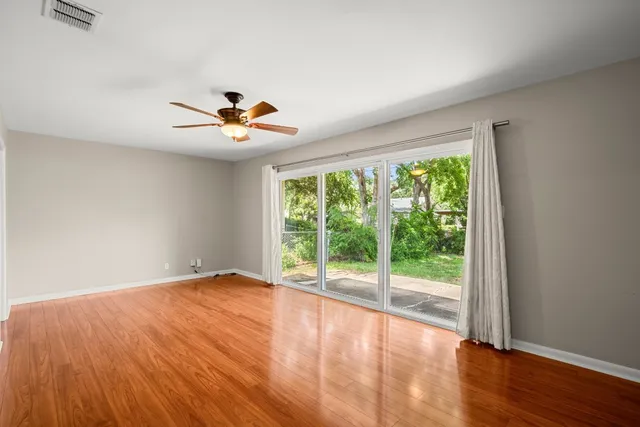 a view of an empty room with wooden floor and a window