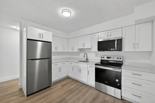 a kitchen with stainless steel appliances a refrigerator stove and white cabinets