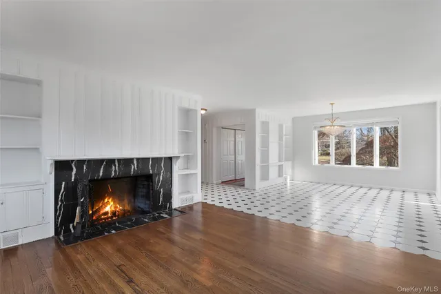 a view of an empty room with wooden floor fireplace and a window