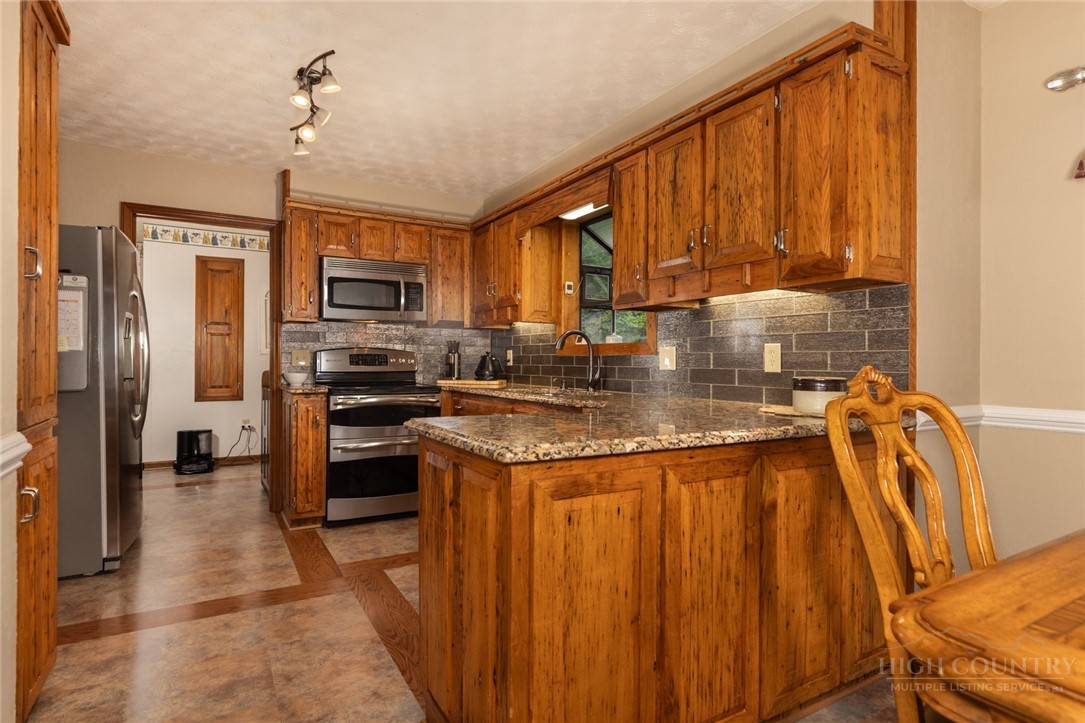 1335 Shingle Gap Road Purlear, NC 28665 - Photo 15 of 49 a kitchen with stainless steel appliances granite countertop a refrigerator a stove top oven a sink and dishwasher