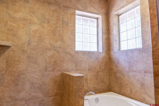 a bathroom with a toilet a sink a window and shower