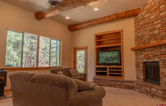 a living room with furniture a flat screen tv and floor to ceiling windows