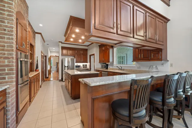 a kitchen with stainless steel appliances granite countertop a table chairs sink and cabinets