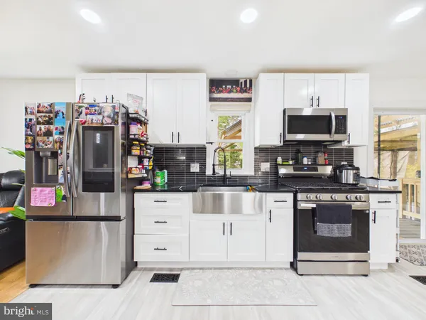 a kitchen with stainless steel appliances granite countertop a stove top oven a sink and a refrigerator