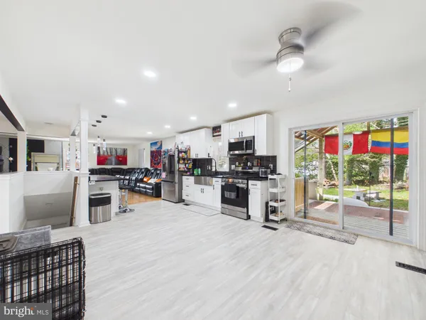 a kitchen view with stainless steel appliances wooden floor and living room view