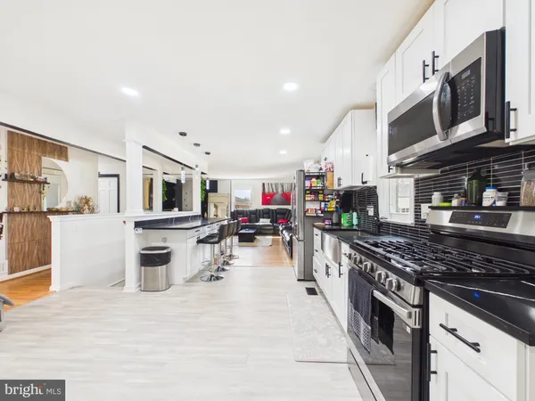 a kitchen with stainless steel appliances granite countertop a stove top oven a sink dishwasher a dining table and chairs with wooden floor