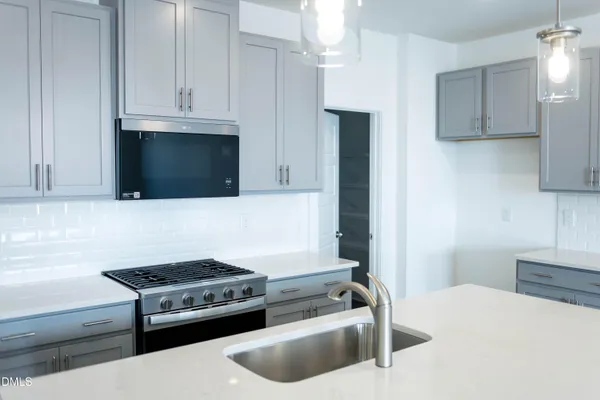 a kitchen with stainless steel appliances a stove a microwave a sink and cabinets