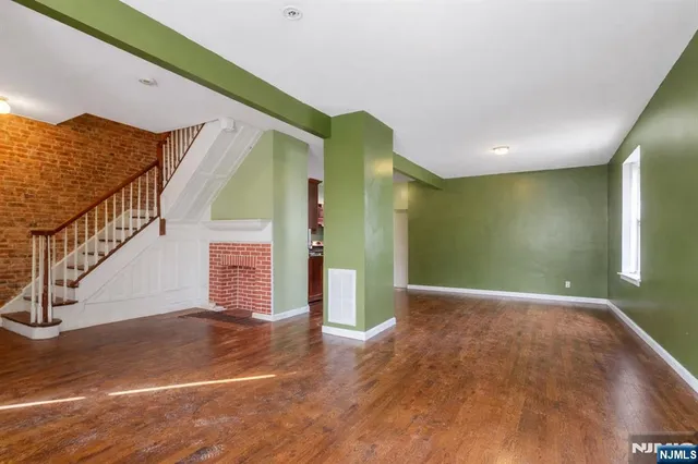 a view of an empty room with wooden floor and a potted plant