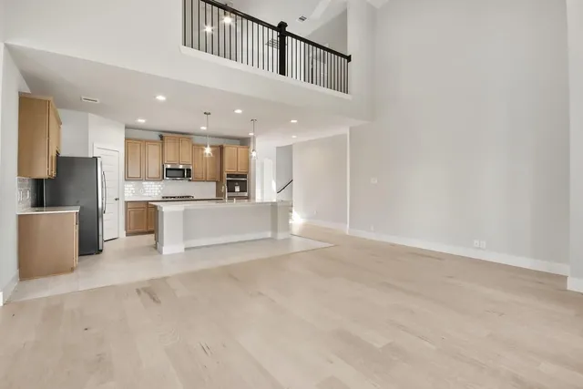 a view of kitchen with kitchen island a sink wooden floor and stainless steel appliances