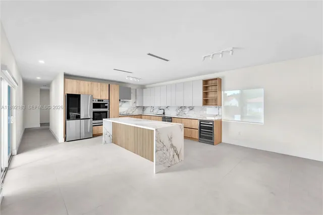 a large white kitchen with stainless steel appliances granite countertop a large counter top and a stove