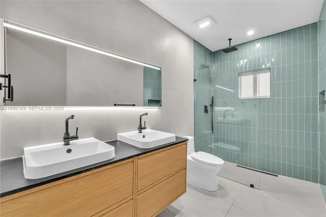 a bathroom with a granite countertop sink a toilet and a mirror