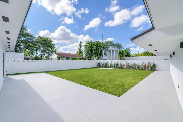 an aerial view of residential houses with outdoor space and trees