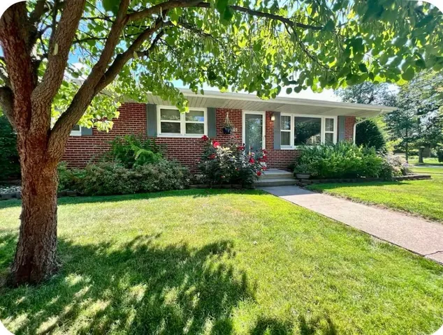 a view of a house with garden and a tree