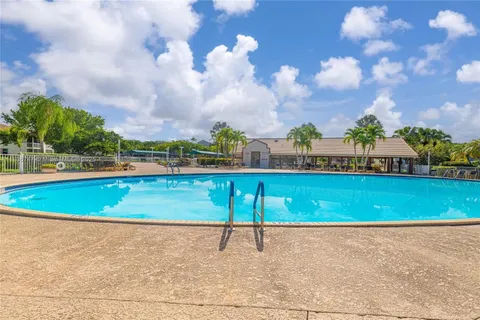 a view of a swimming pool with a lounge chair and trees in the background