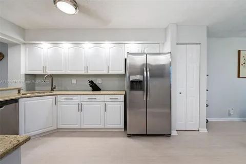 a kitchen with granite countertop a refrigerator sink and cabinets