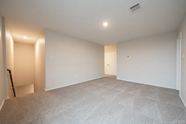 a view of an empty room with a chandelier fan