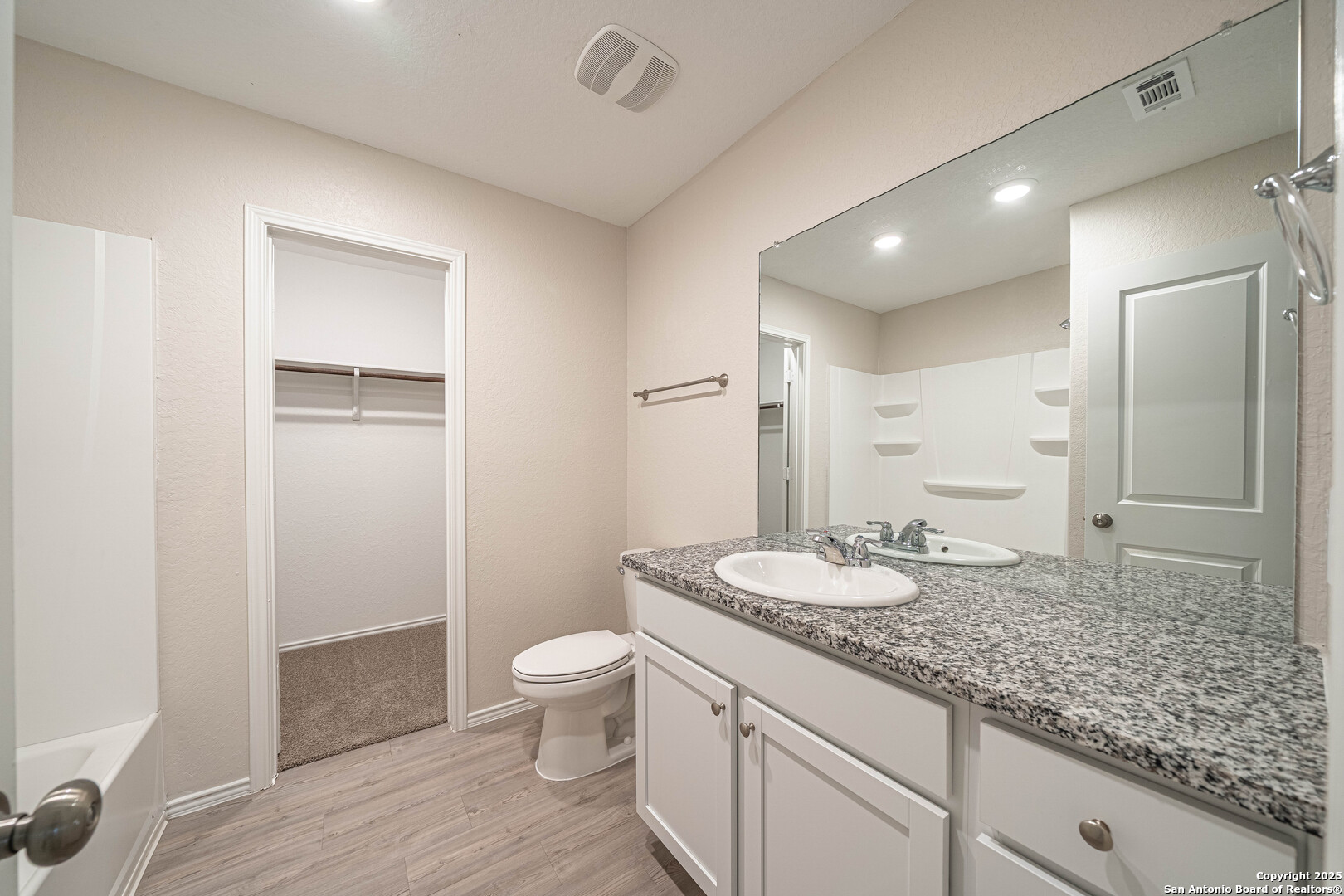 2818 Gustavo Drive Converse, TX 78109 - Photo 14 of 27 a bathroom with a granite countertop sink a toilet a mirror and shower