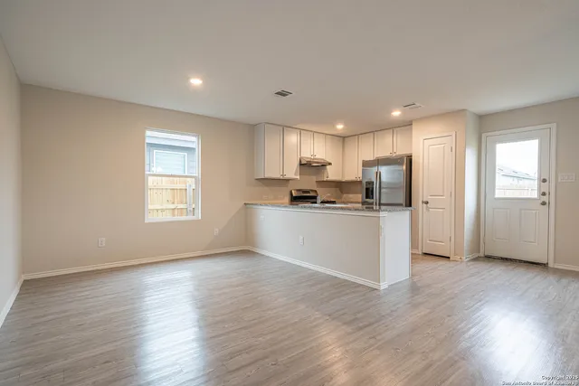 a view of an empty room with window and wooden floor