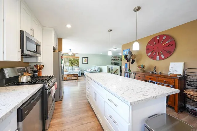 a large kitchen with stainless steel appliances granite countertop a stove a sink dishwasher and a dining table with wooden floor