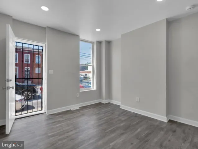 an empty room with wooden floor and windows