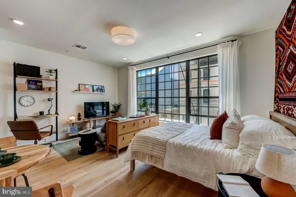 a bedroom with a bed a large window and a flat screen tv