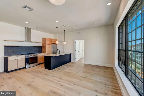 a large kitchen with stainless steel appliances granite countertop a stove a refrigerator a sink and a oven with wooden floor