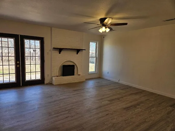 a view of a livingroom with wooden floor a ceiling fan and window