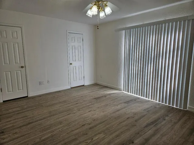an empty room with wooden floor chandelier and windows