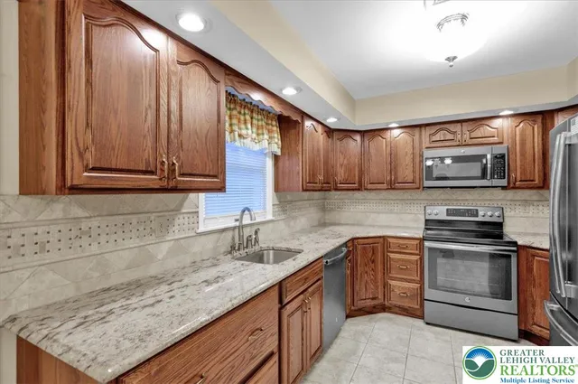 a kitchen with stainless steel appliances granite countertop wooden cabinets a stove top oven a sink and dishwasher