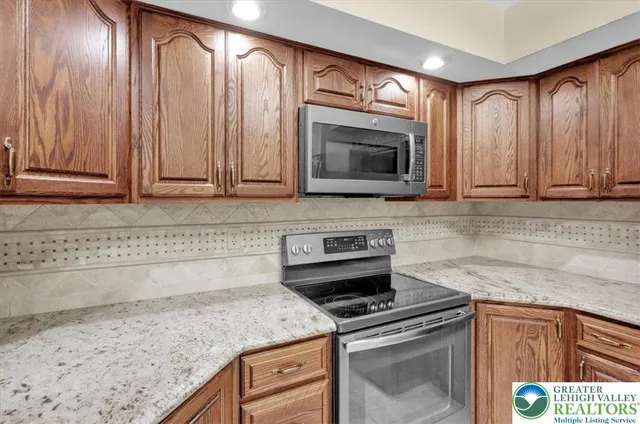 a kitchen with granite countertop wood cabinets stainless steel appliances and a counter space