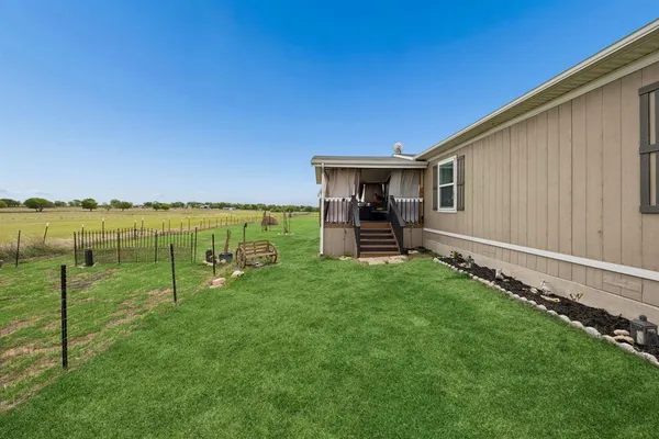 a view of a backyard with lawn chairs and iron fence