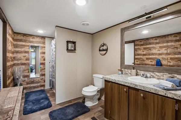 a bathroom with a granite countertop sink a toilet a mirror and shower