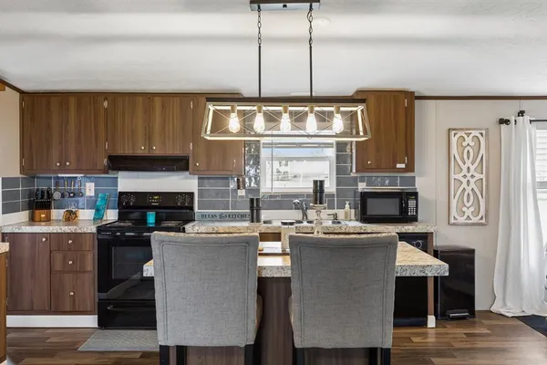 a kitchen with stainless steel appliances granite countertop a stove top oven a sink a counter space and cabinets