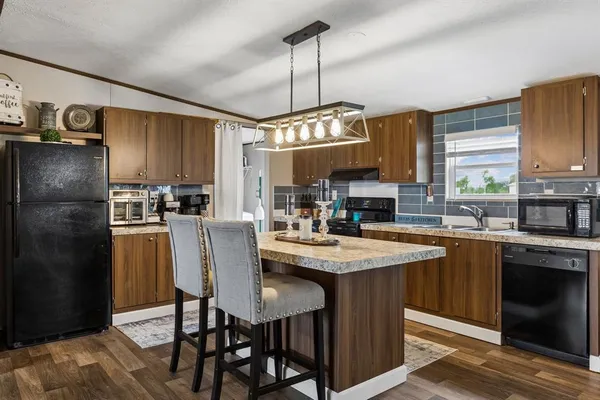 a kitchen with stainless steel appliances granite countertop a sink a stove a refrigerator and cabinets