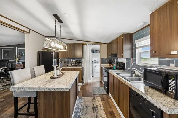a kitchen with granite countertop kitchen island stainless steel appliances a sink stove and refrigerator