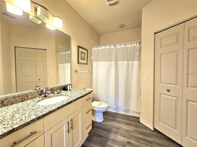 a bathroom with a granite countertop sink a toilet a mirror and shower