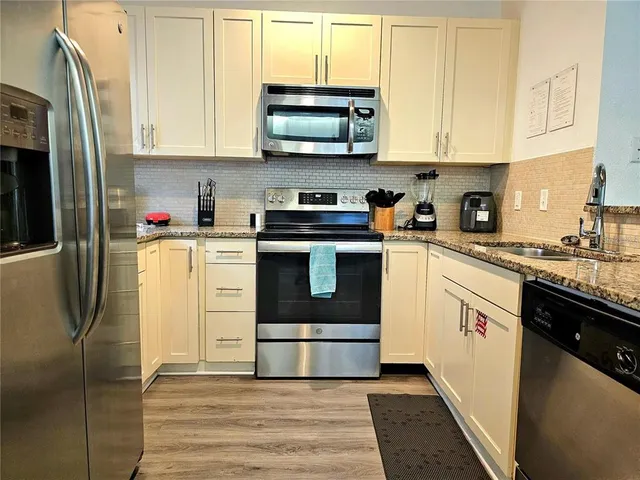 a kitchen with stainless steel appliances granite countertop a stove a sink and a refrigerator