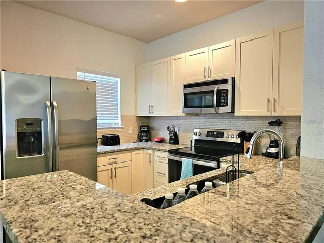 a kitchen with stainless steel appliances granite countertop a stove top oven a refrigerator and a sink