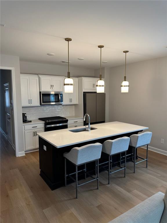 1925 Appian Alley Kennesaw, GA 30144 - Photo 5 of 27 a kitchen with stainless steel appliances kitchen island a table chairs in it and white cabinets