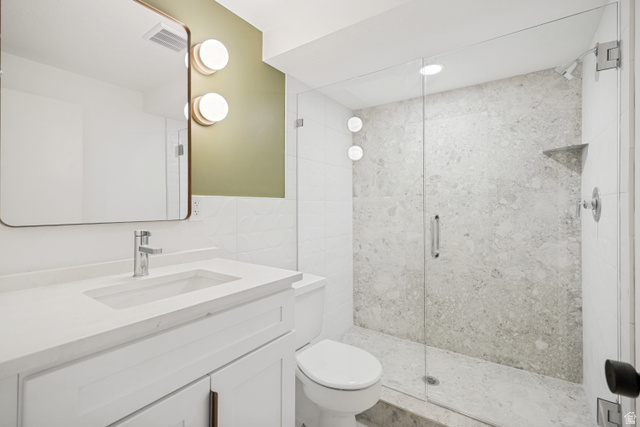 1168 East Center Street Bountiful, UT 84010 - Photo 32 of 38 Full bathroom featuring a frameless glass shower enclosure, a built-in shower niche, a white vanity with an integrated sink, a contemporary chrome faucet, and a rectangular wall mirror with rounded corners