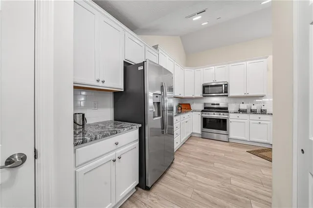 a kitchen with white cabinets and stainless steel appliances