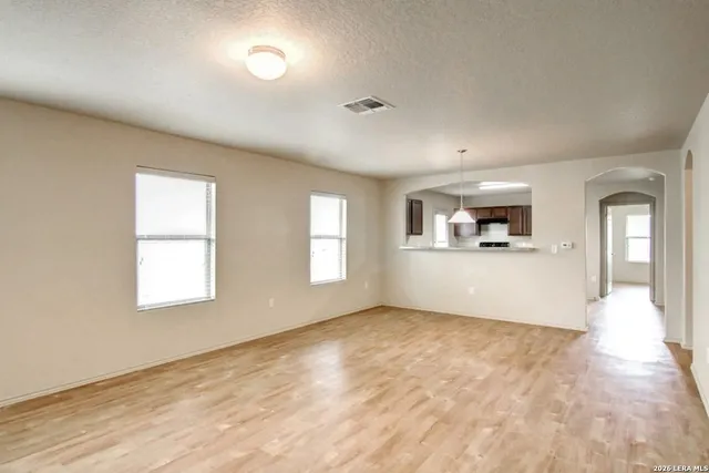 a view of an empty room with a window and wooden floor