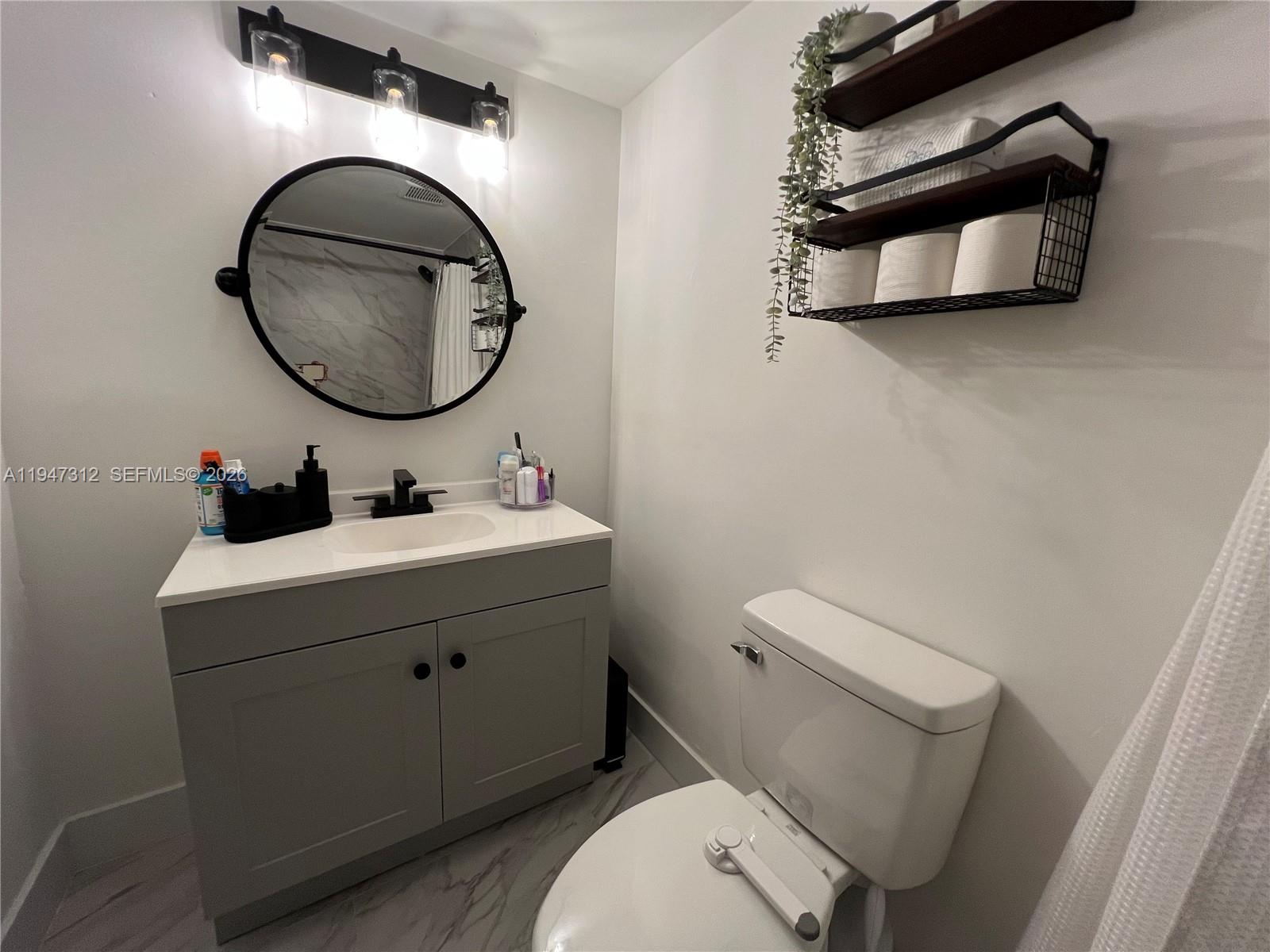 8425 Northwest 8th Street, Unit 406 Miami, FL 33126 - Photo 19 of 22 a bathroom with a toilet sink vanity and mirror