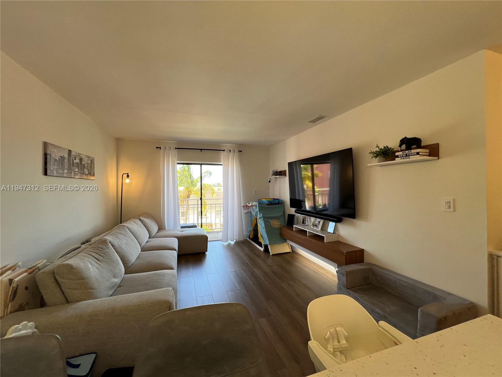 8425 Northwest 8th Street, Unit 406 Miami, FL 33126 - Photo 4 of 22 a living room with furniture and a flat screen tv