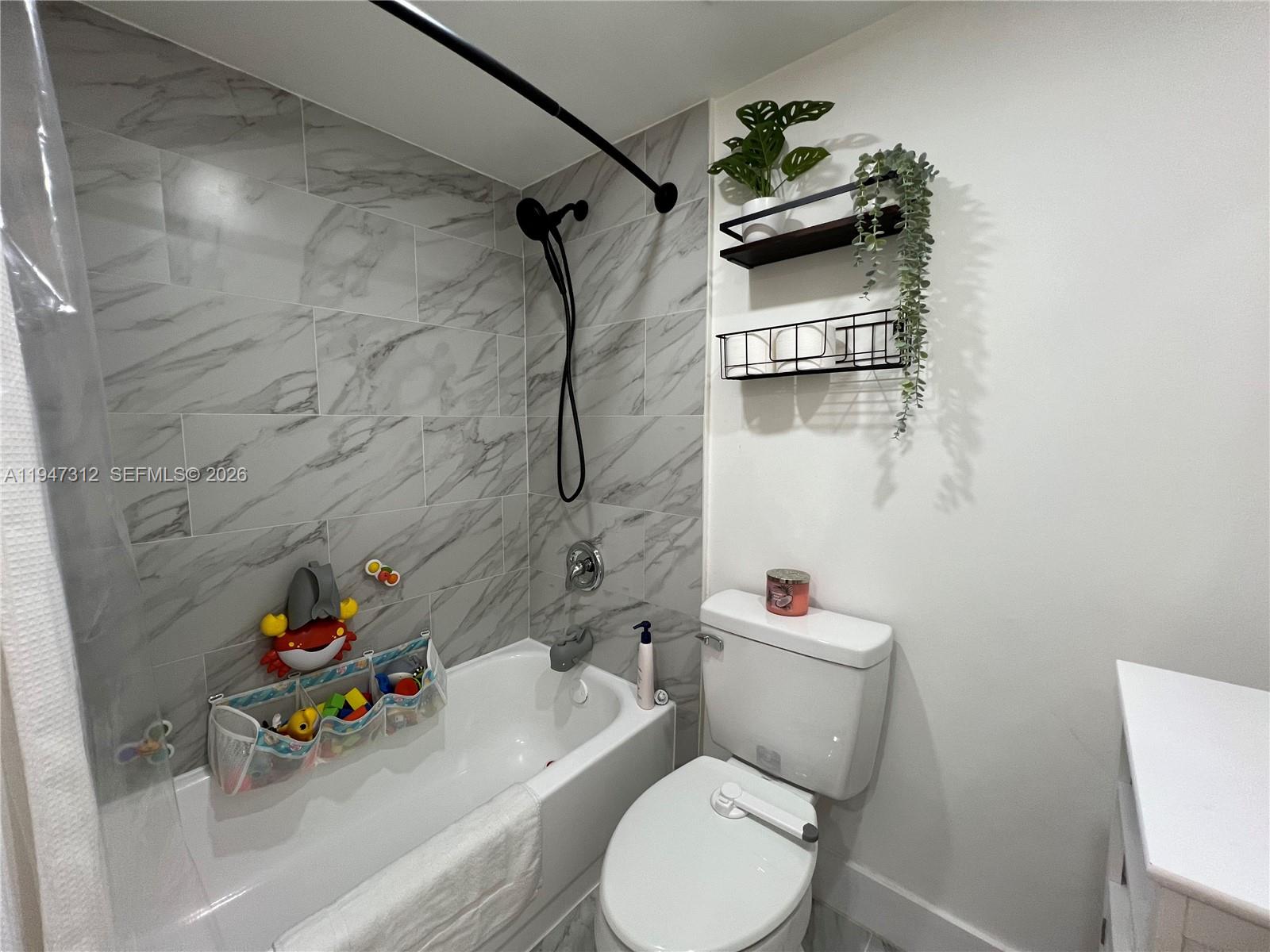 8425 Northwest 8th Street, Unit 406 Miami, FL 33126 - Photo 10 of 22 a white toilet sitting next to a bathroom sink and tub