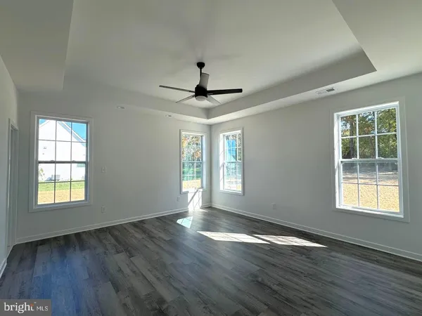 a view of an empty room with wooden floor and window