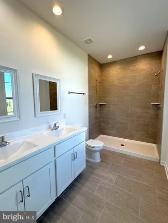 a bathroom with a double vanity sink a toilet and shower